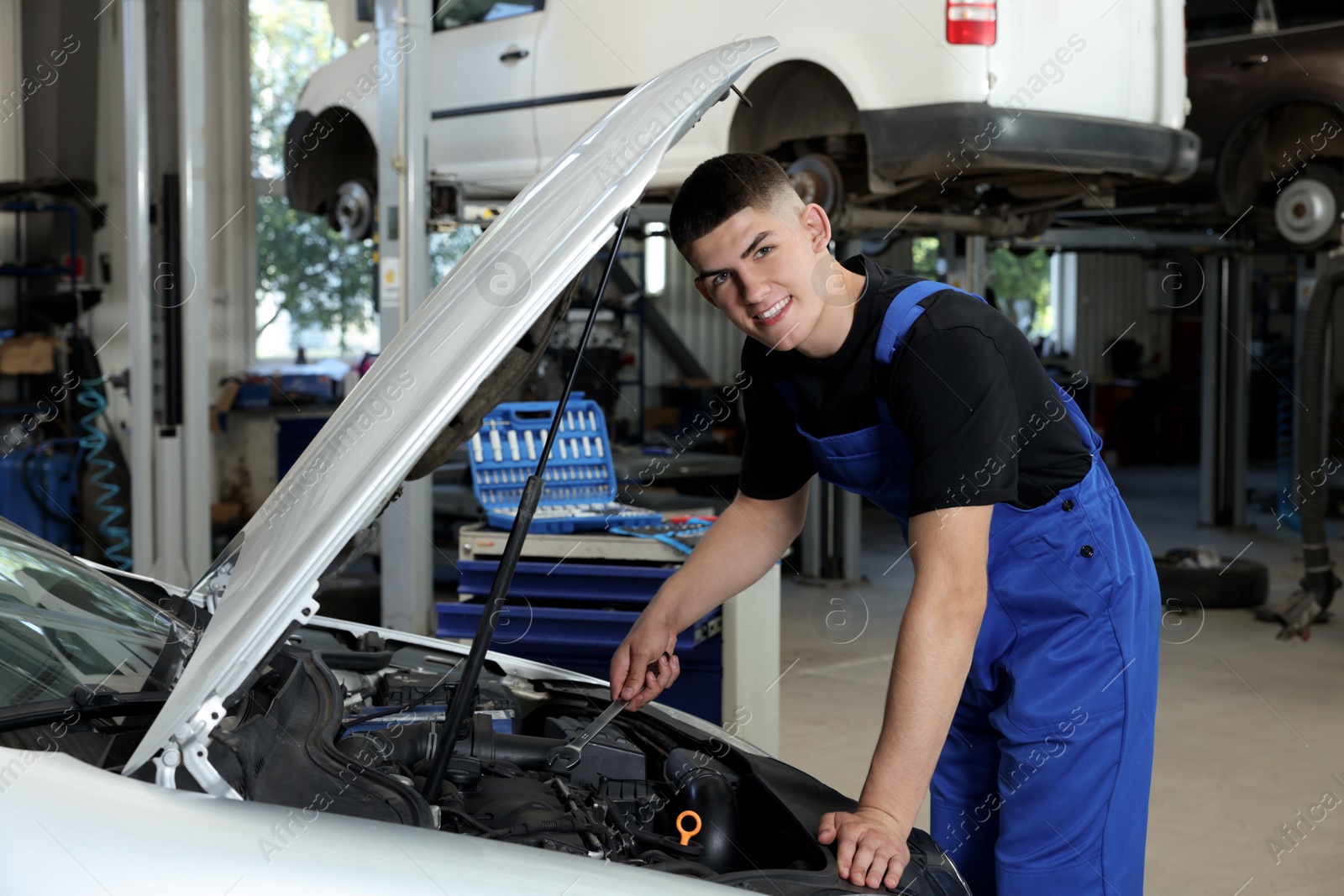 Photo of Young auto mechanic fixing car at automobile repair shop