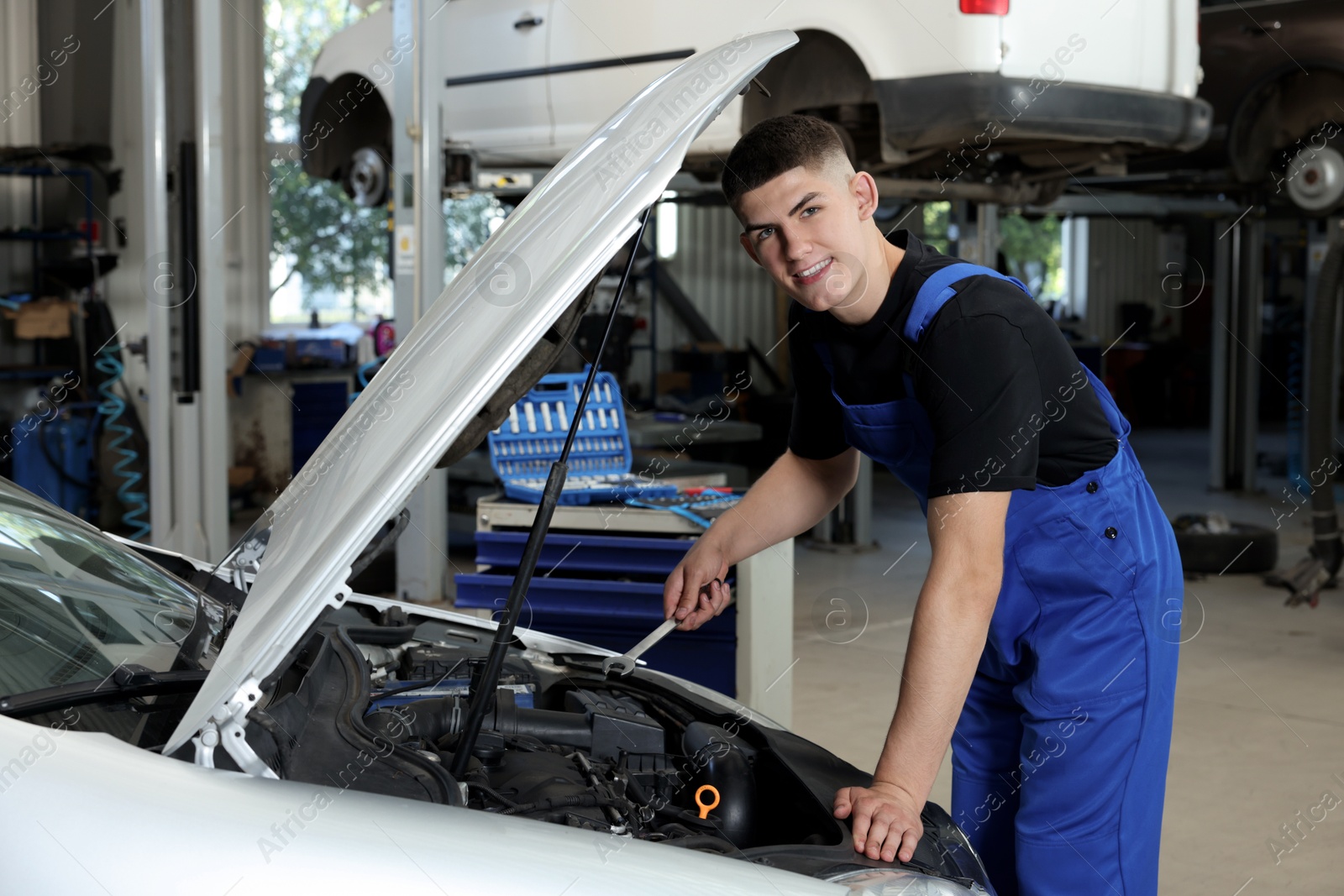 Photo of Young auto mechanic fixing car at automobile repair shop