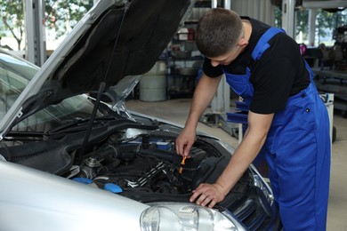 Photo of Young auto mechanic fixing car at automobile repair shop