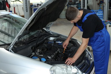 Photo of Young auto mechanic fixing car at automobile repair shop