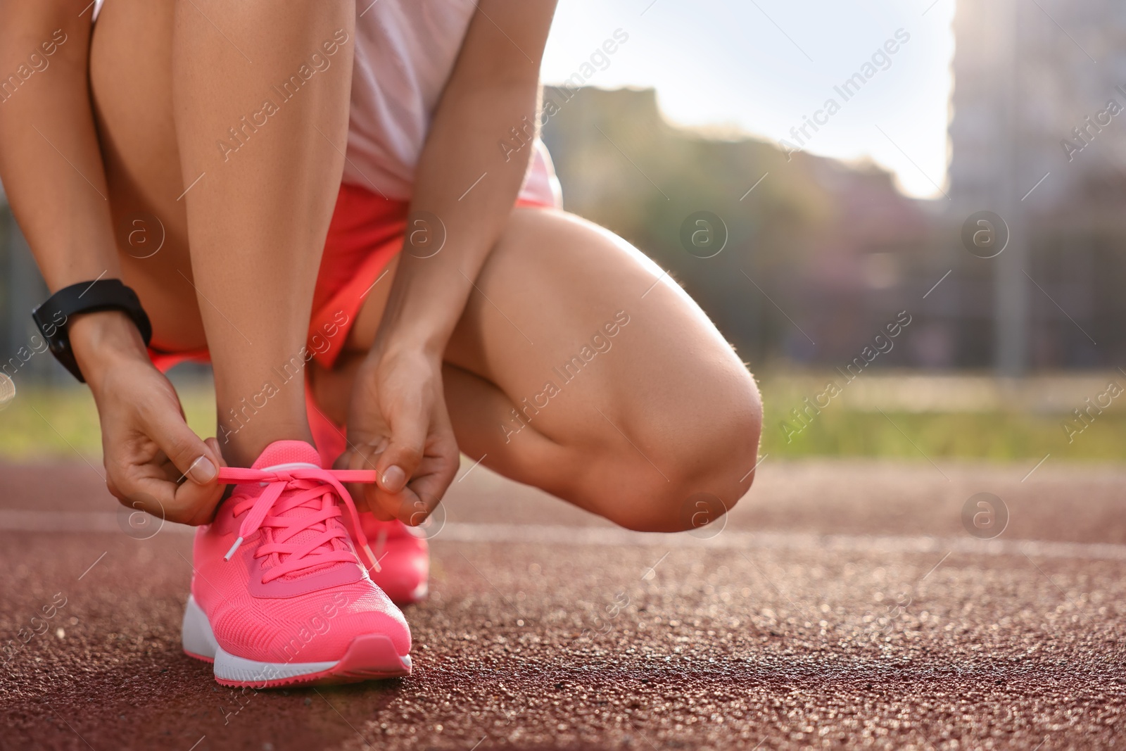 Photo of Woman tying shoelace of pink sneaker at stadium, closeup. Space for text