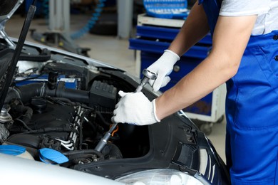 Auto mechanic fixing car at automobile repair shop, closeup