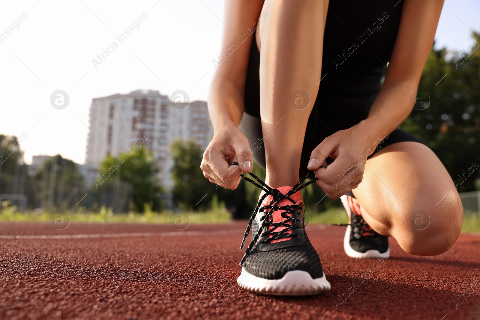 Photo of Woman tying shoelace of sneaker at stadium, closeup. Space for text