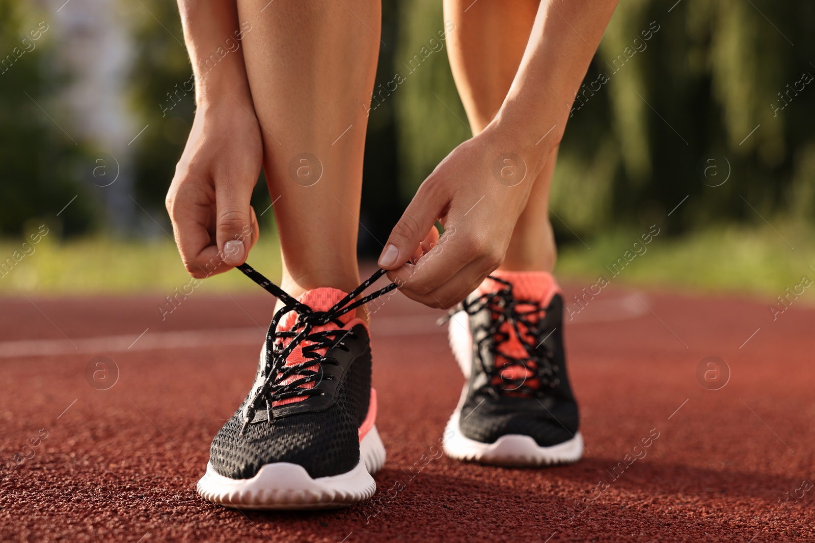 Photo of Woman tying shoelace of sneaker at stadium, closeup