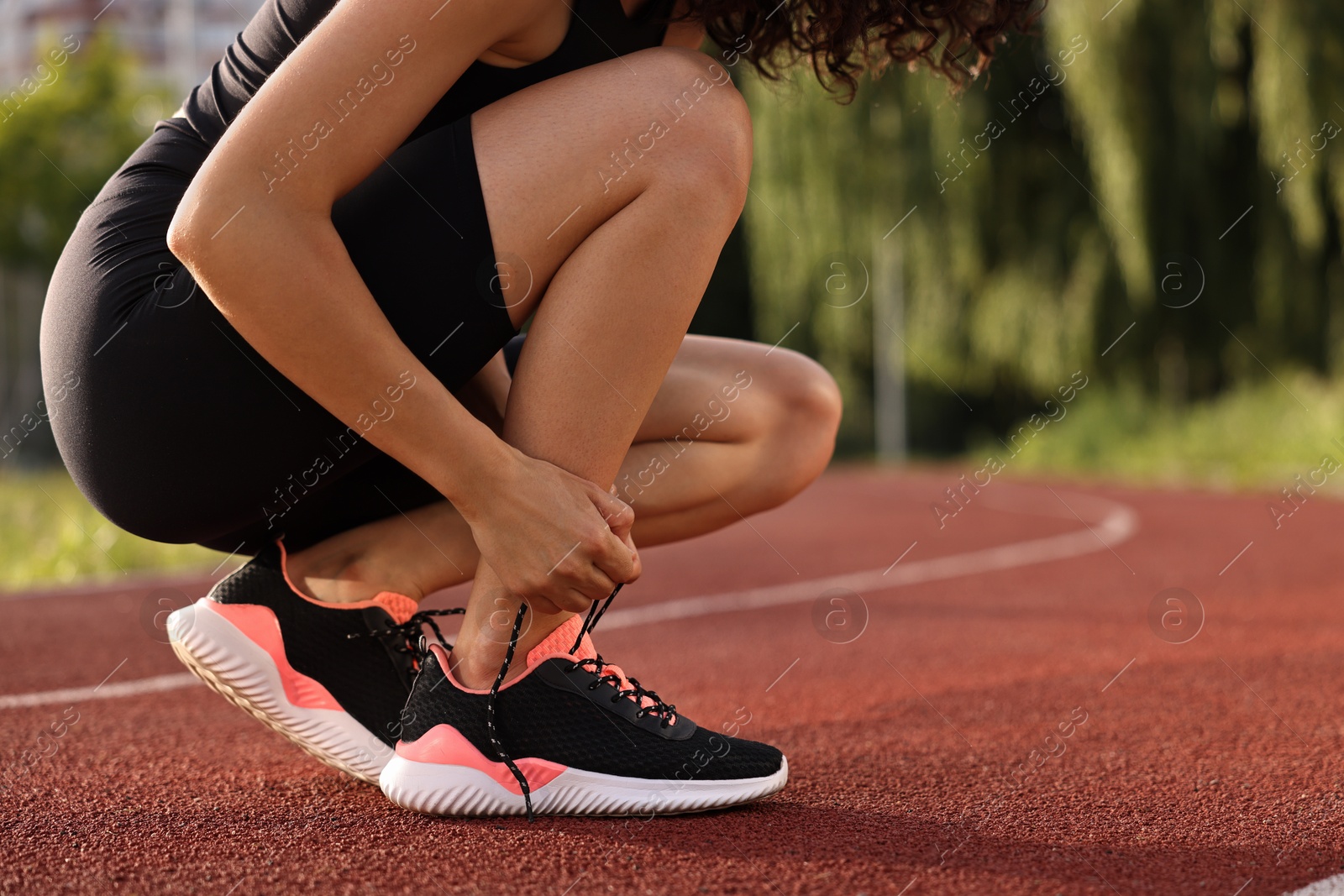 Photo of Woman tying shoelace of sneaker at stadium, closeup. Space for text