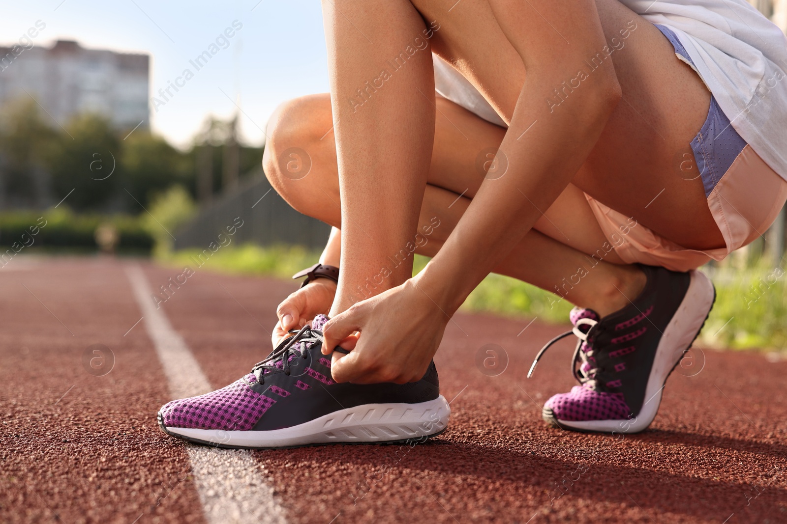 Photo of Woman tying shoelace of sneaker at stadium, closeup