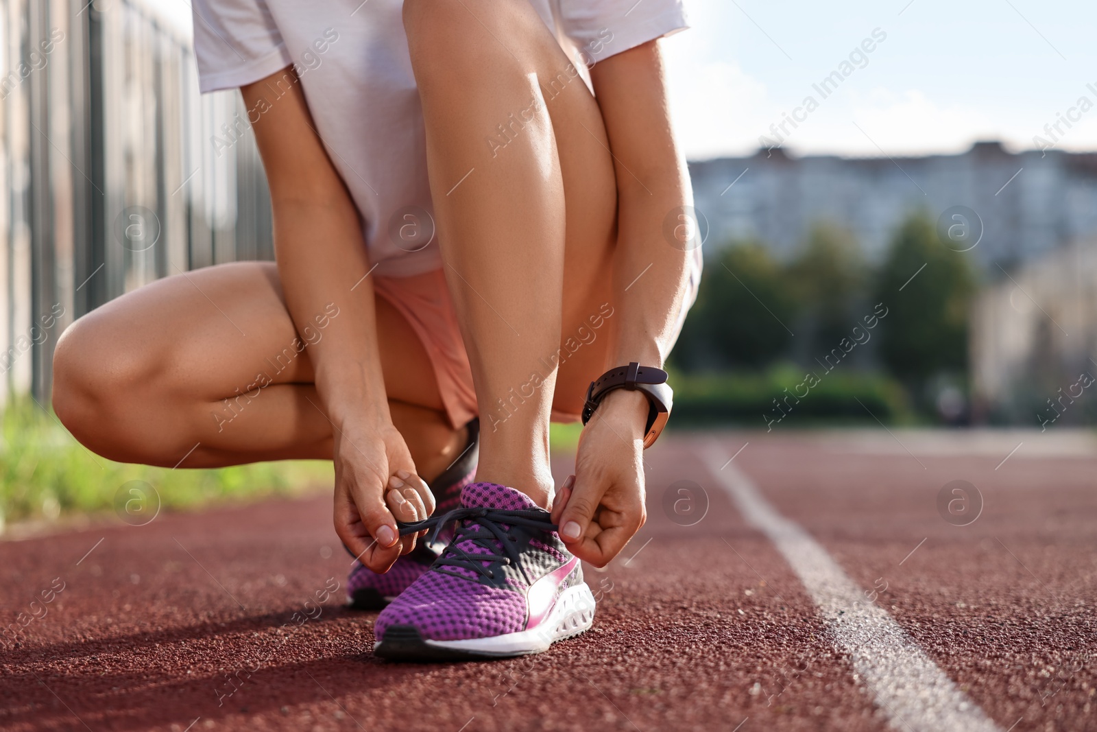 Photo of Woman tying shoelace of sneaker at stadium, closeup. Space for text