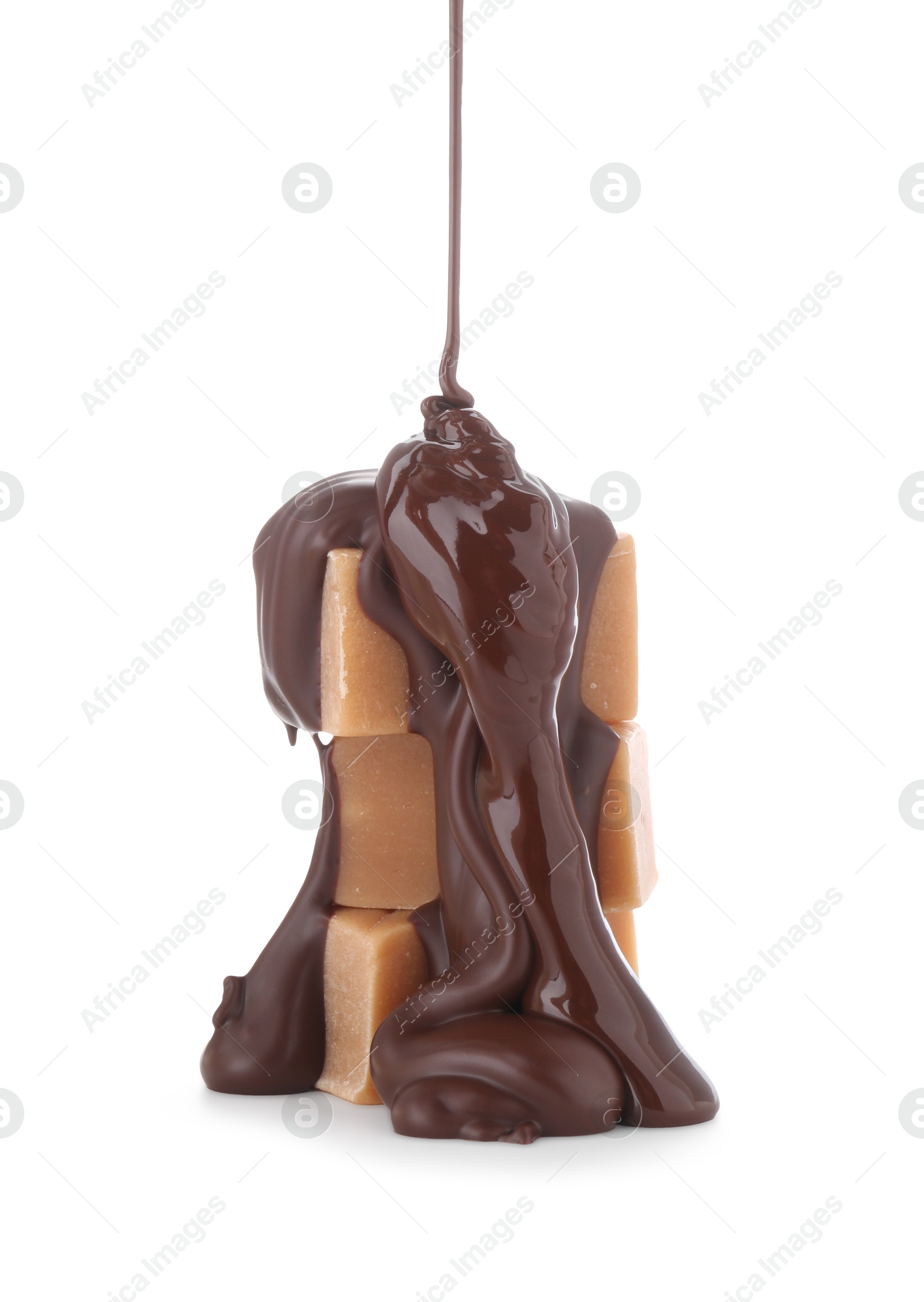 Photo of Pouring delicious melted chocolate onto caramel candies isolated on white