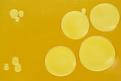 Photo of Sample of cosmetic oil on dark yellow background, macro view