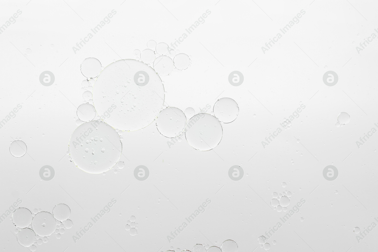 Photo of Essential oil bubbles on white background, macro view. Cosmetic product