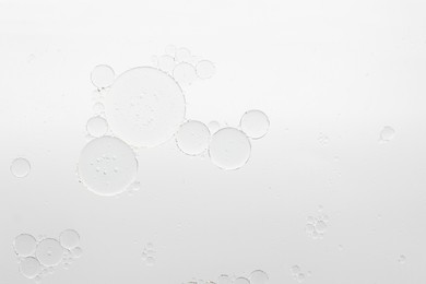 Photo of Essential oil bubbles on white background, macro view. Cosmetic product