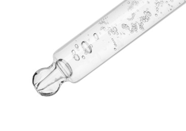 Dripping cosmetic serum from pipette on white background