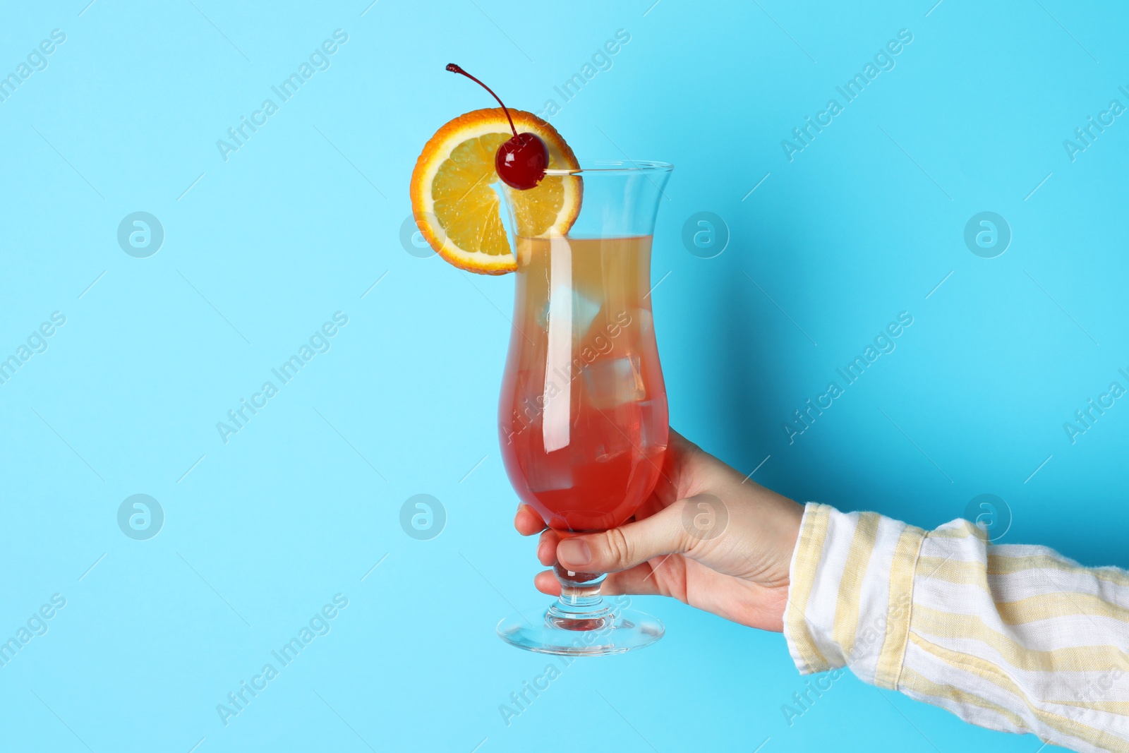 Photo of Woman with glass of refreshing cocktail on light blue background, closeup