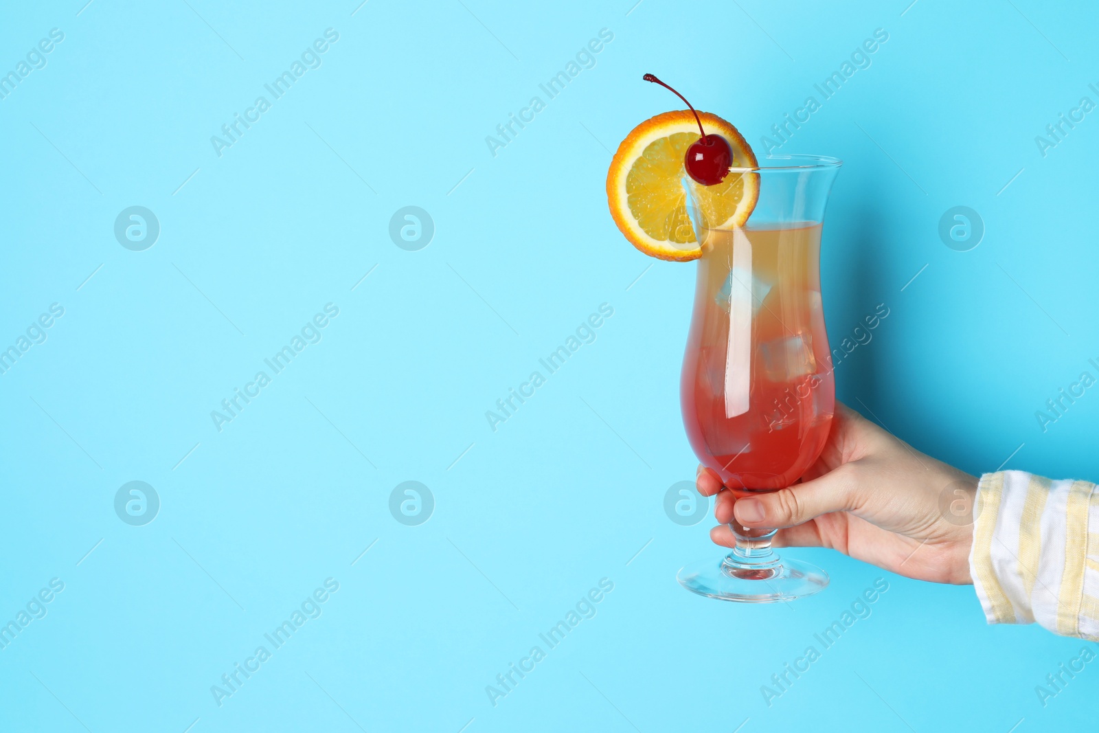 Photo of Woman with glass of refreshing cocktail on light blue background, closeup