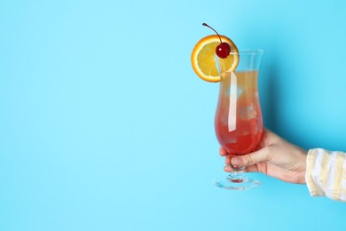 Photo of Woman with glass of refreshing cocktail on light blue background, closeup