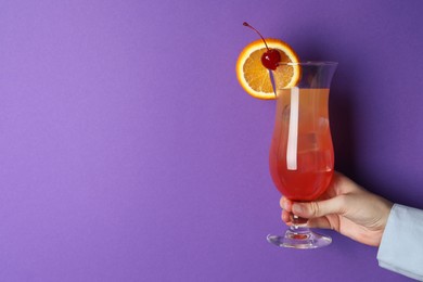 Photo of Woman with glass of refreshing cocktail on purple background, closeup. Space for text