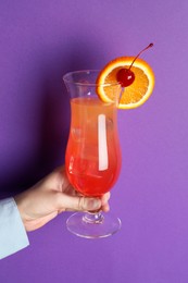 Photo of Woman with glass of refreshing cocktail on purple background, closeup