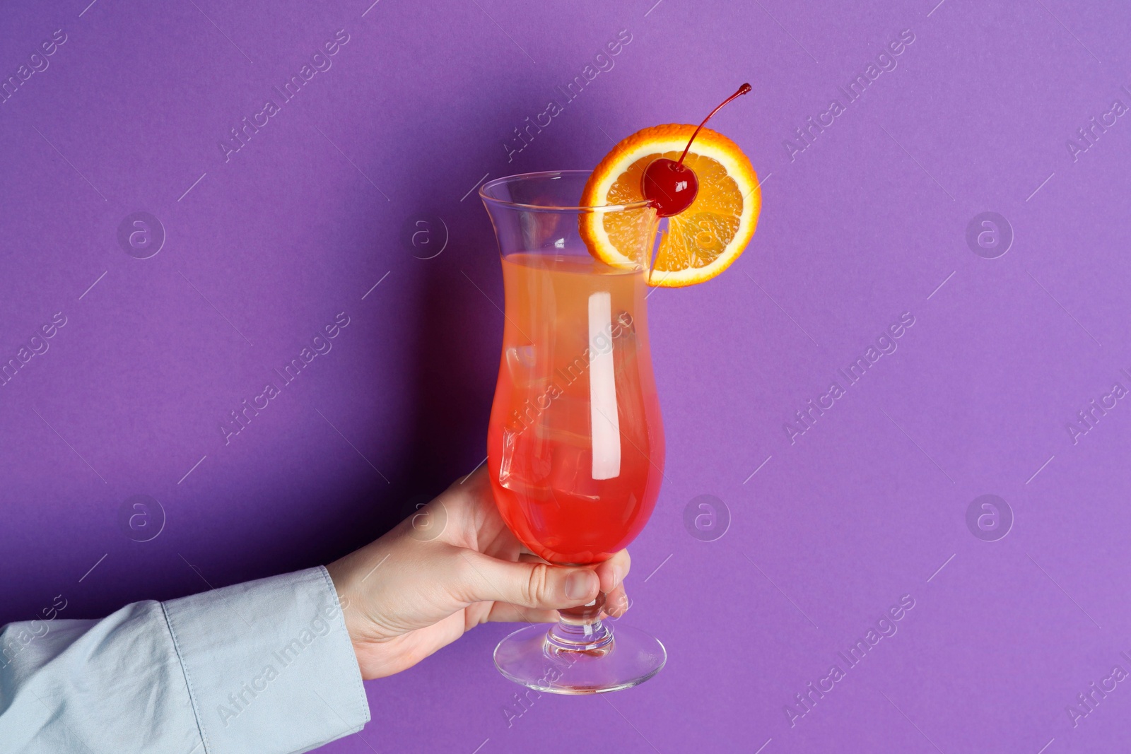 Photo of Woman with glass of refreshing cocktail on purple background, closeup