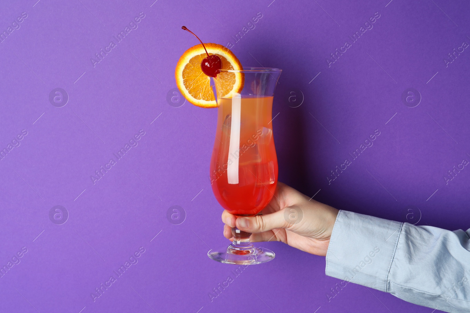 Photo of Woman with glass of refreshing cocktail on purple background, closeup