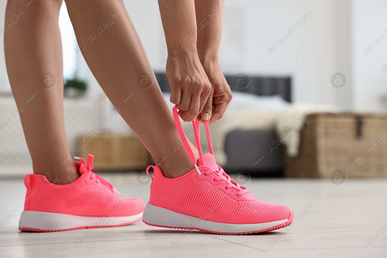 Photo of Woman tying shoelace of pink sneaker indoors, closeup. Space for text