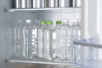 Cans of beer and water bottles in refrigerator, closeup