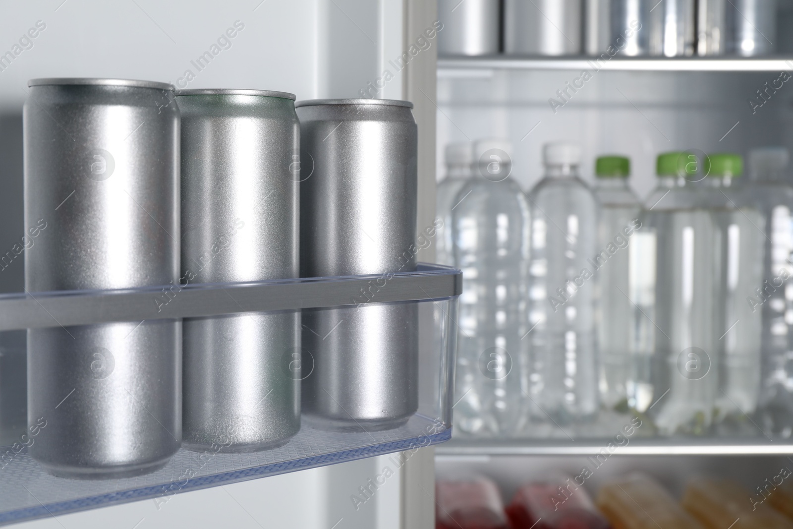 Photo of Cans of beer and water bottles in refrigerator, closeup