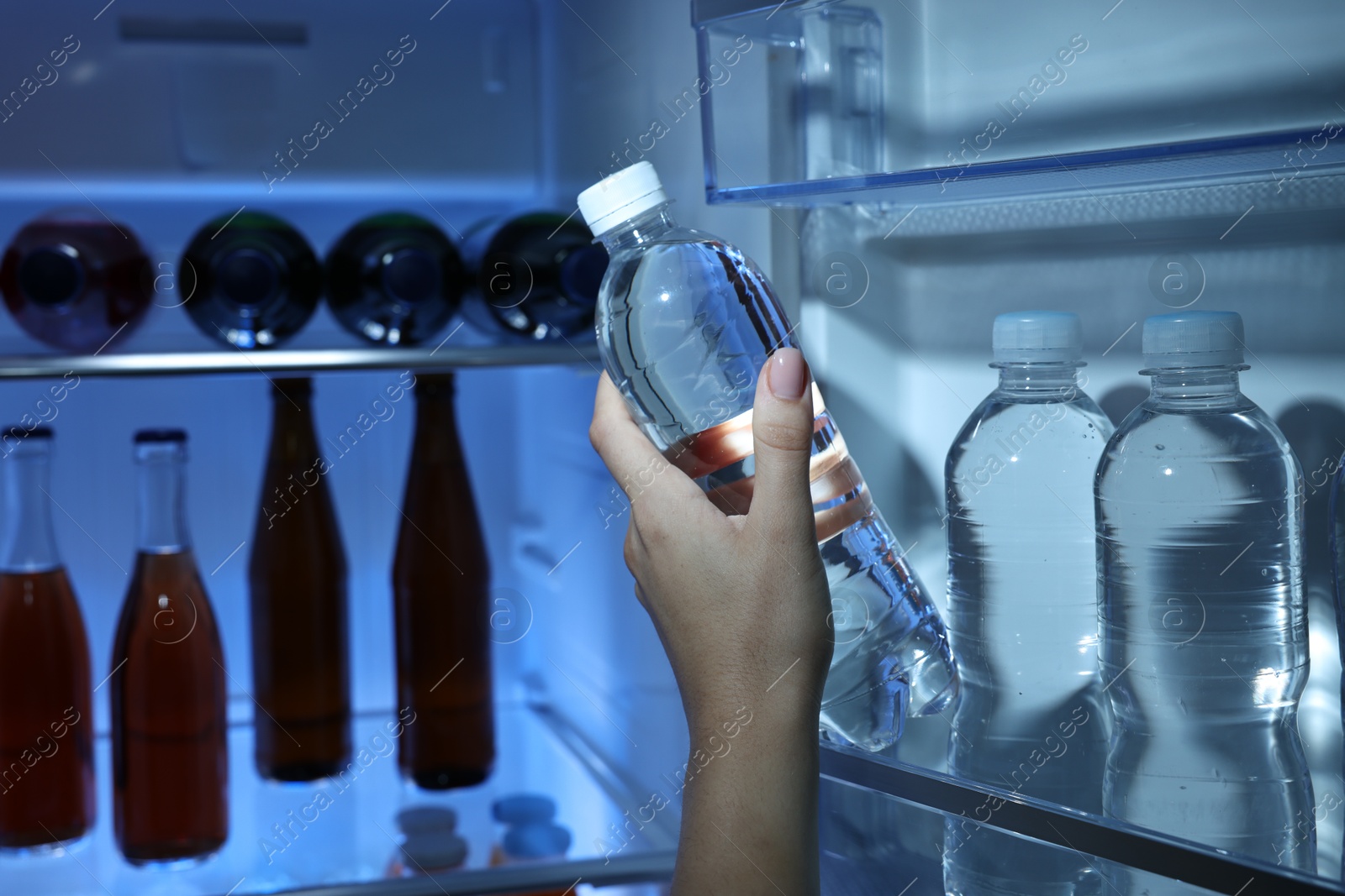 Photo of Woman taking bottle of water from refrigerator, closeup