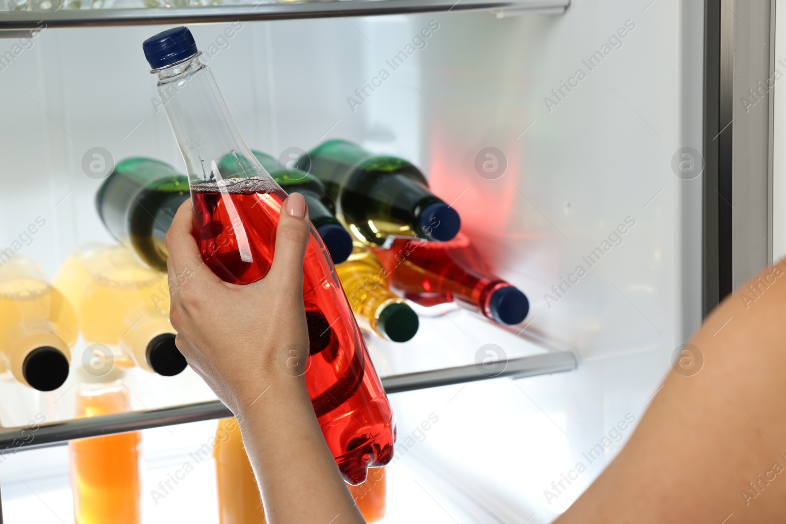 Photo of Woman taking bottle with drink from refrigerator, closeup