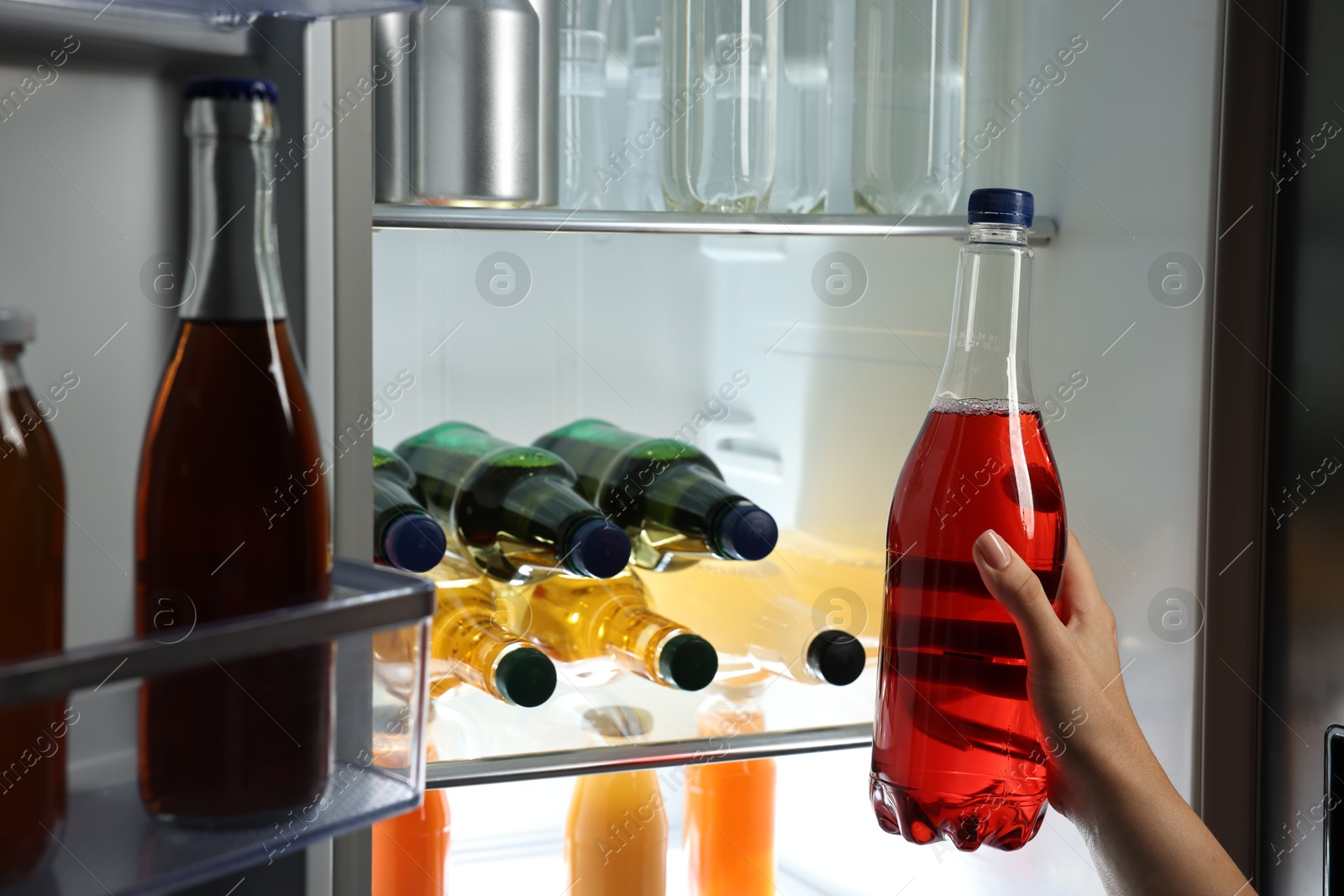 Photo of Woman taking bottle with drink from refrigerator, closeup