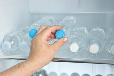 Photo of Woman taking bottle of water from refrigerator, closeup