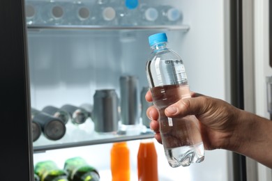 Woman taking bottle of water from refrigerator, closeup