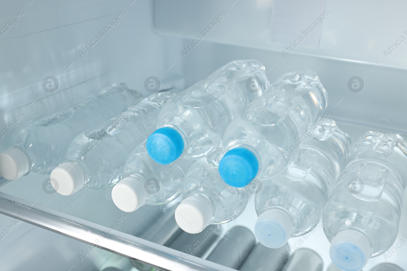 Photo of Many bottles of water in refrigerator, closeup