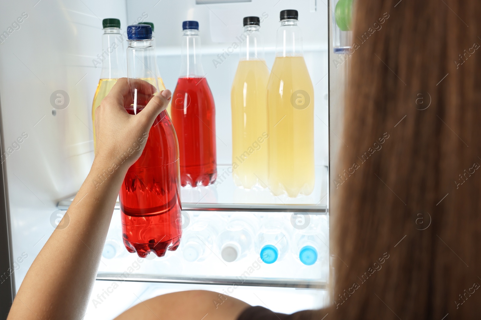 Photo of Woman taking bottle with drink from refrigerator, closeup