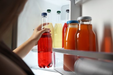 Photo of Woman taking bottle with drink from refrigerator, closeup