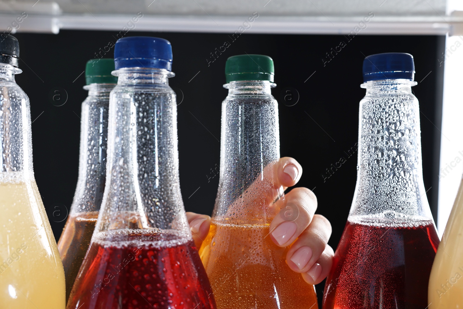 Photo of Woman taking bottle of soda drink from refrigerator, closeup