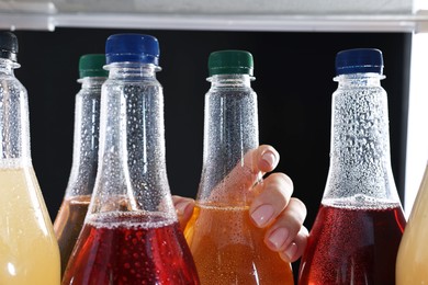 Photo of Woman taking bottle of soda drink from refrigerator, closeup