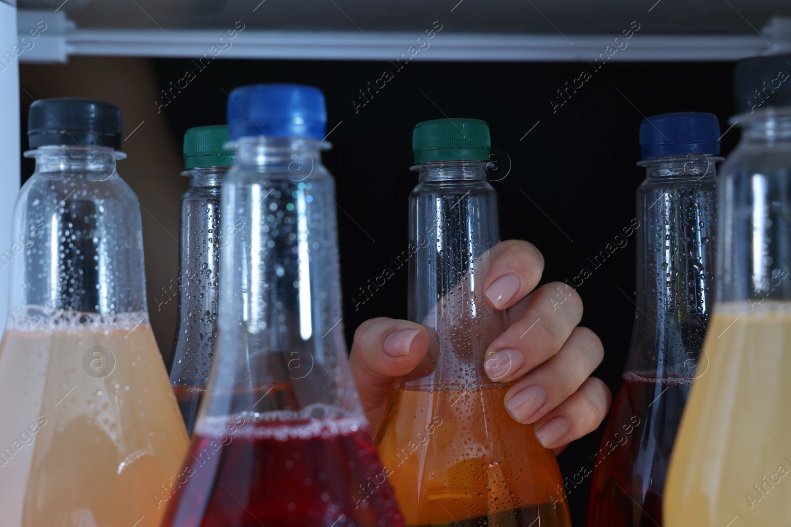 Photo of Woman taking bottle of soda drink from refrigerator, closeup