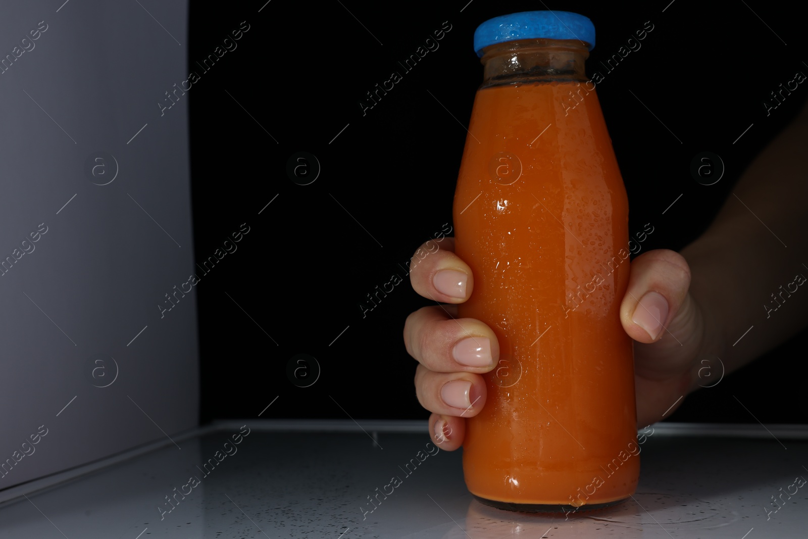 Photo of Woman taking bottle of juice from refrigerator, closeup. Space for text