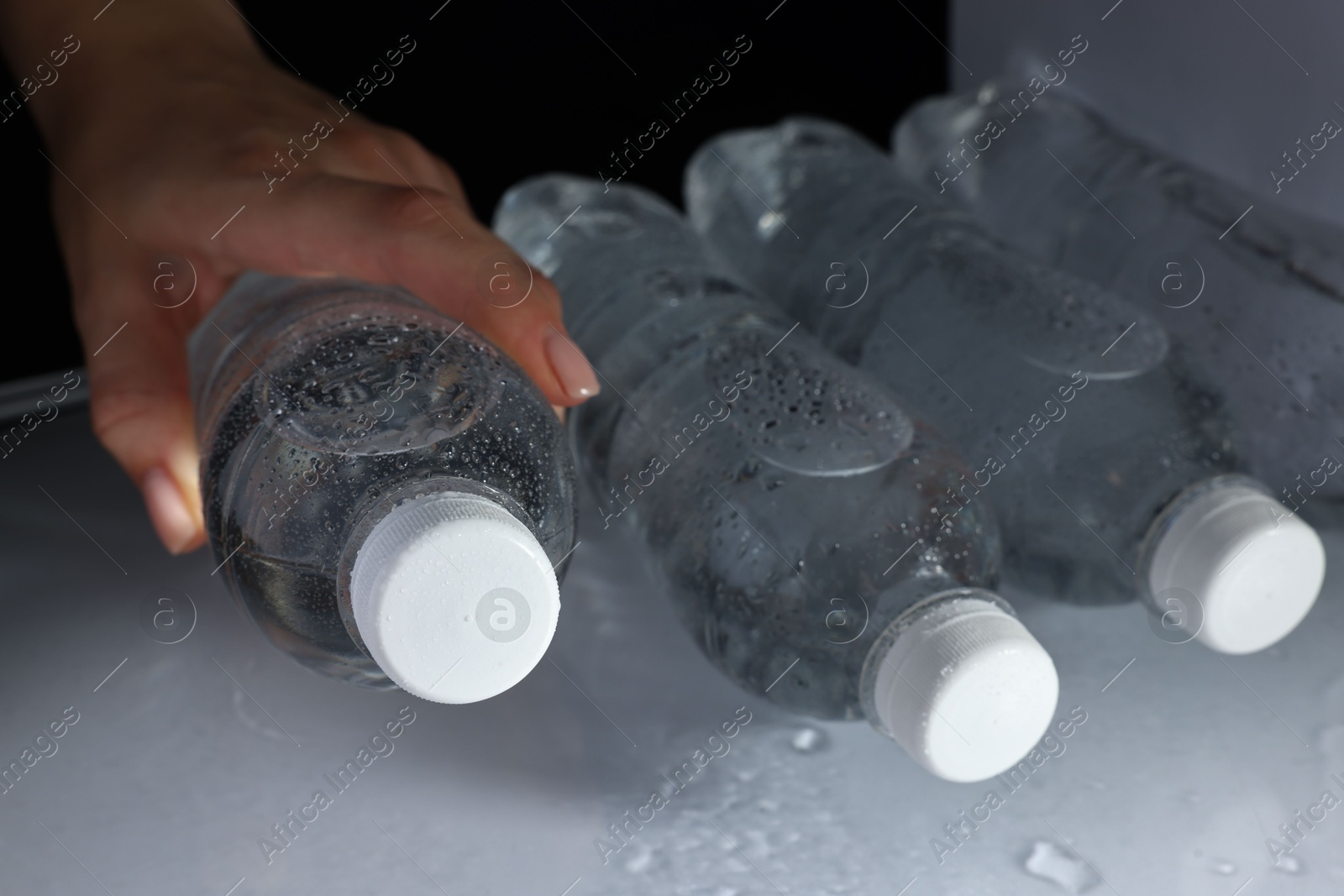 Photo of Woman taking bottle of water from refrigerator, closeup