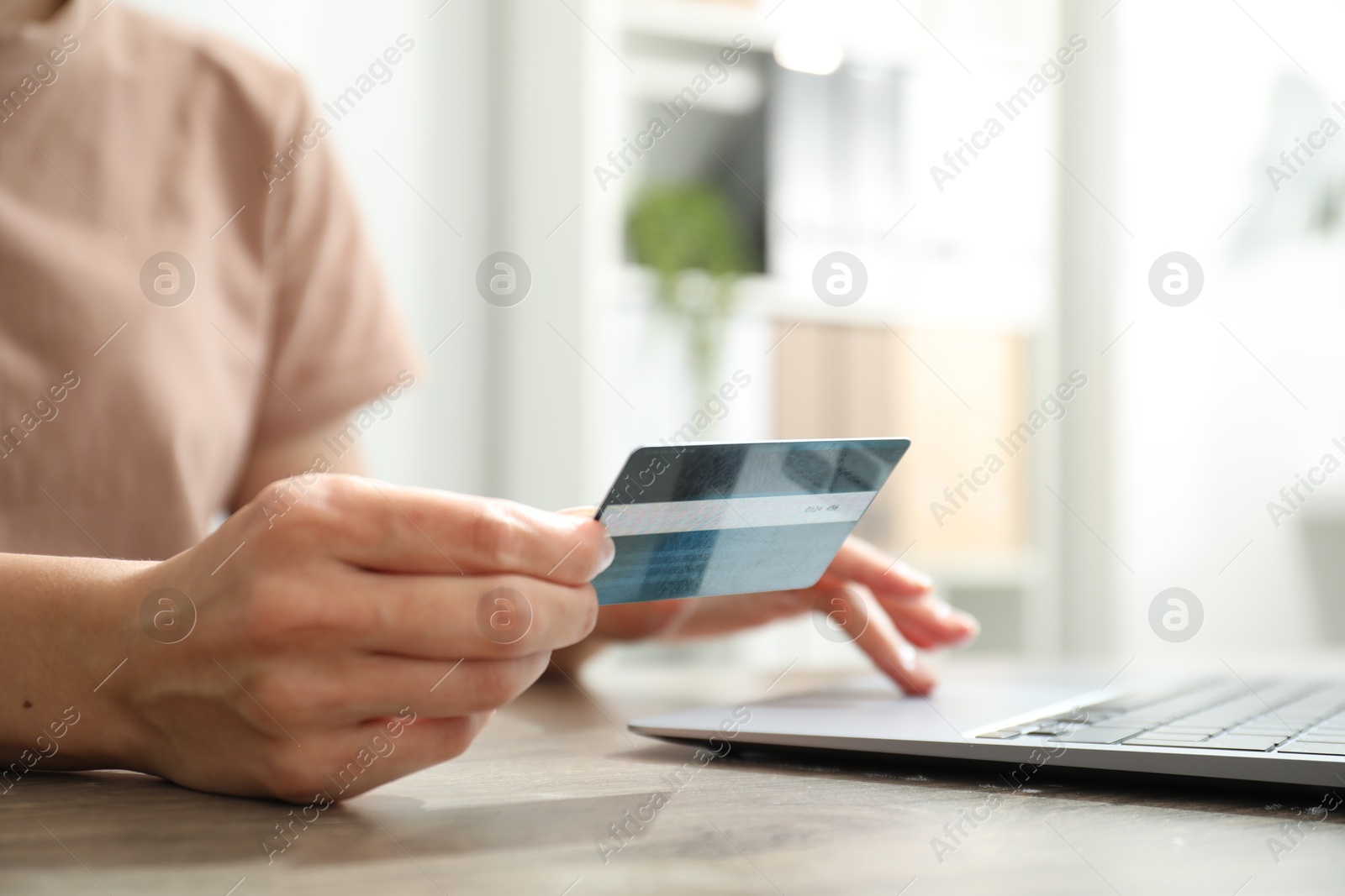 Photo of Woman with credit card using laptop at wooden table indoors, closeup