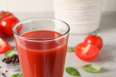 Tasty tomato juice in glass, basil leaves and fresh vegetables on table, closeup