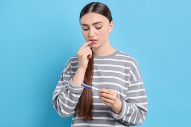 Photo of Woman holding pregnancy test on light blue background