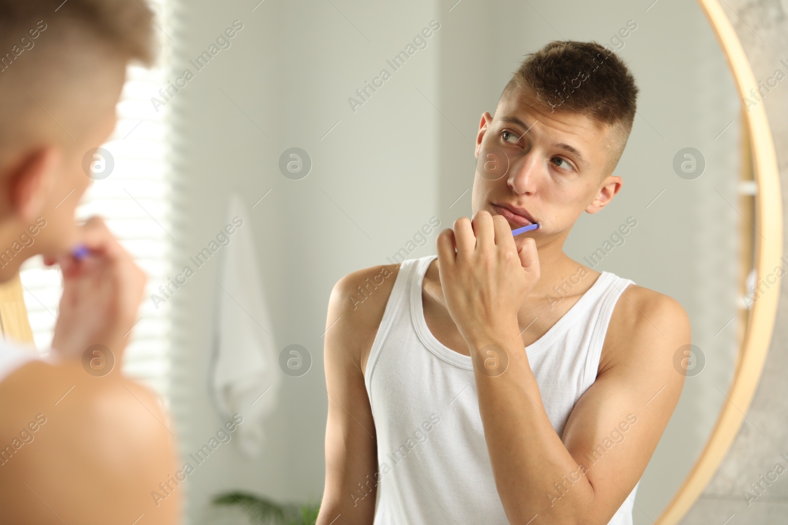 Photo of Young man brushing his teeth in bathroom