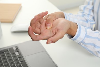 Photo of Carpal tunnel syndrome. Woman suffering from pain in wrist at desk, closeup