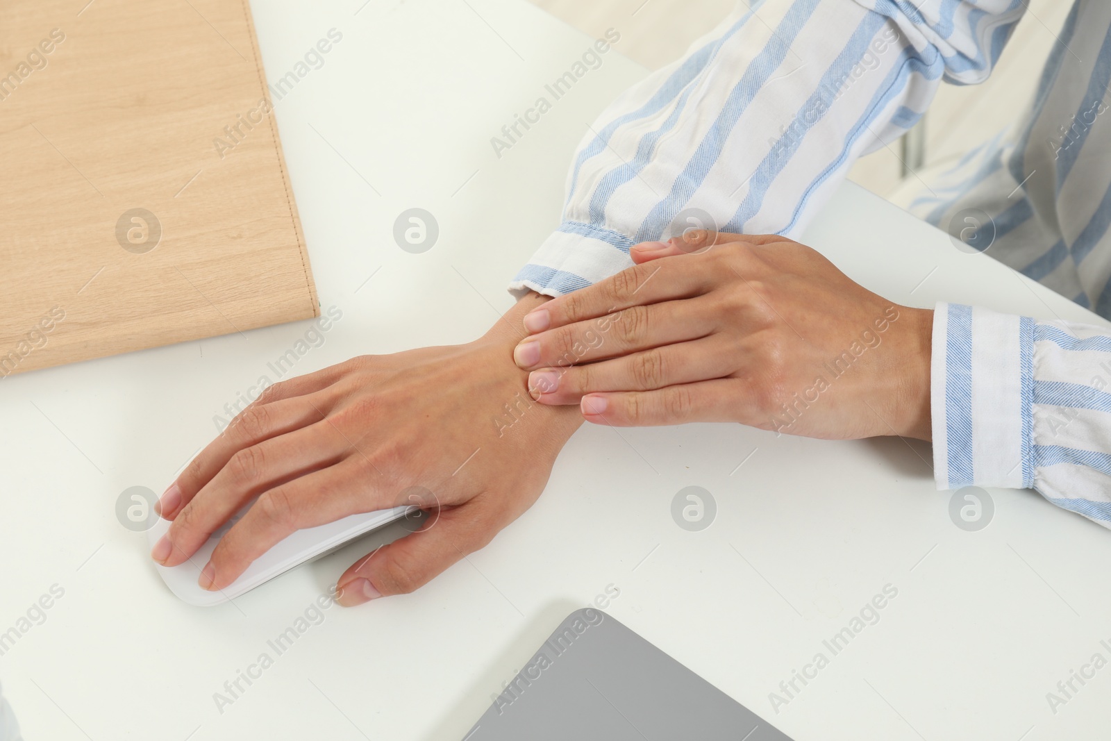 Photo of Carpal tunnel syndrome. Woman suffering from pain in wrist at desk, closeup