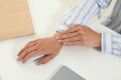 Photo of Carpal tunnel syndrome. Woman suffering from pain in wrist at desk, closeup