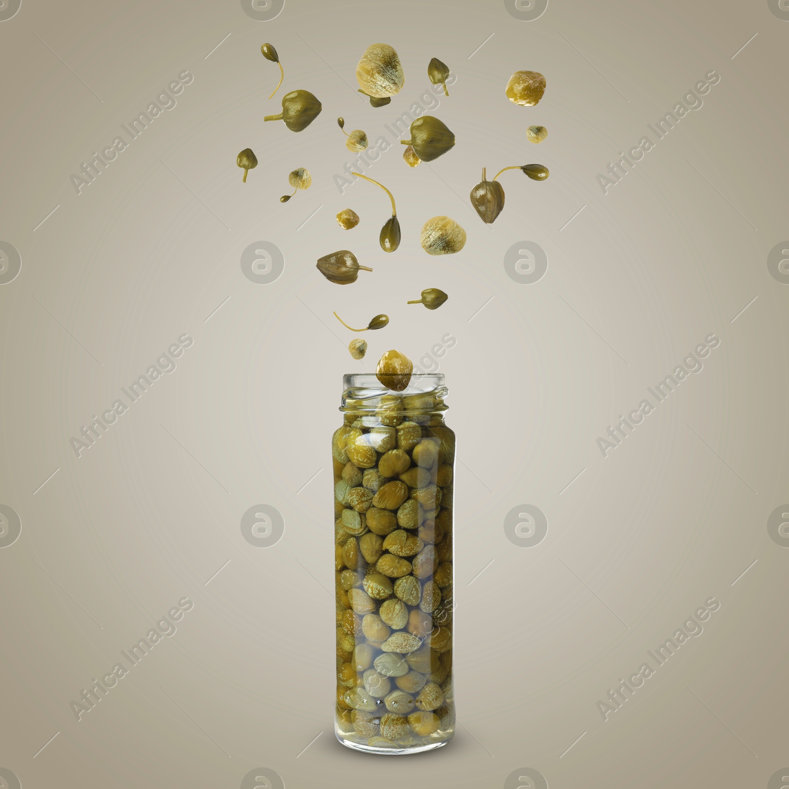 Image of Capers falling into jar on dark beige background