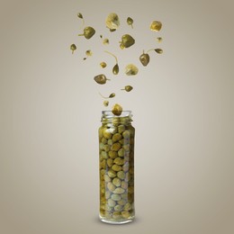 Image of Capers falling into jar on dark beige background