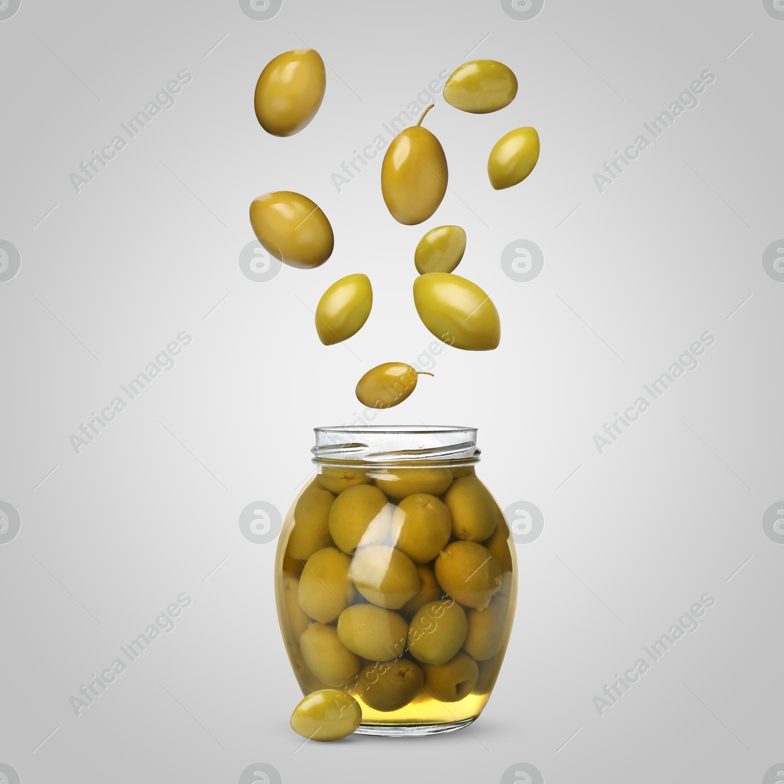 Image of Olives falling into jar on light grey background