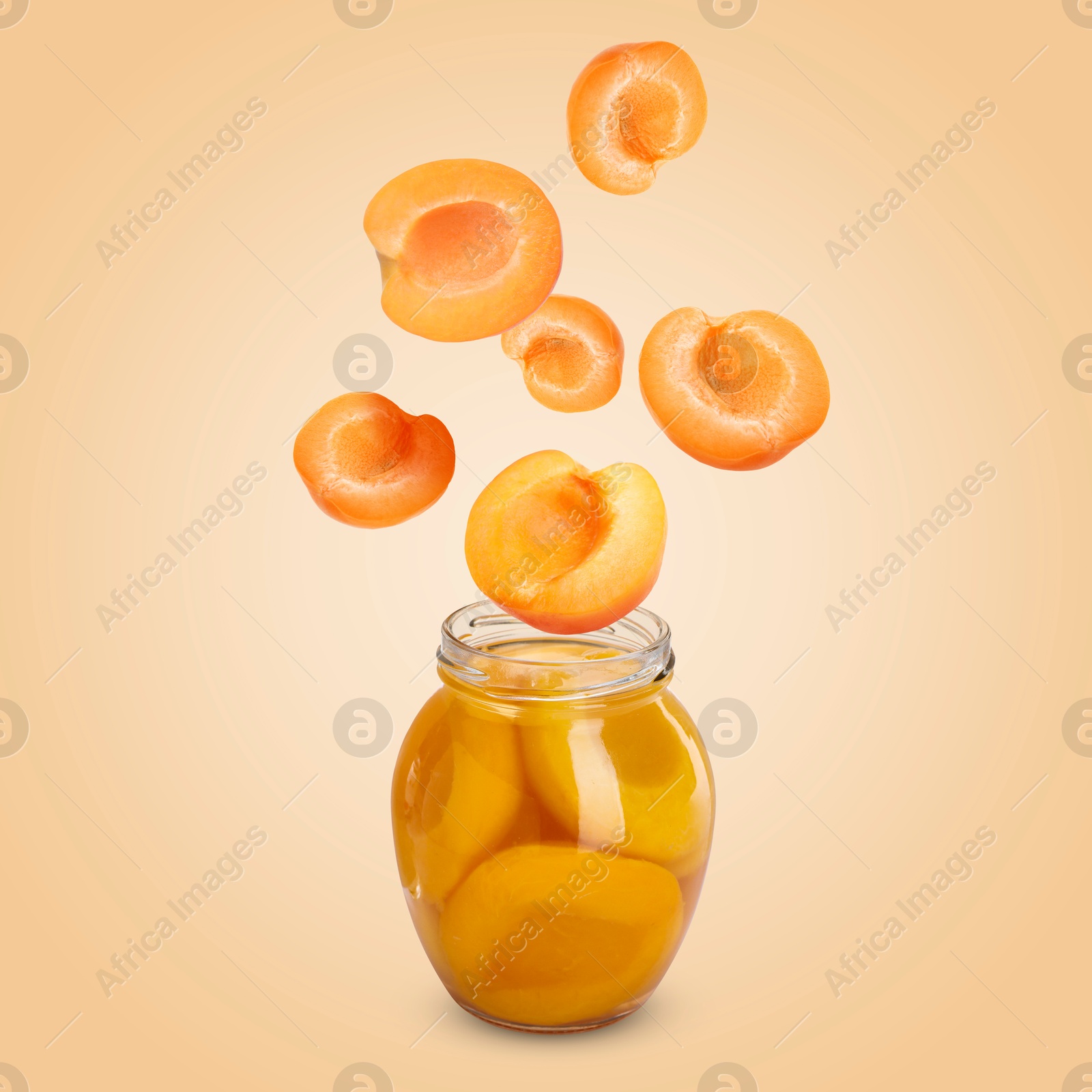 Image of Apricots falling into jar on pale orange background